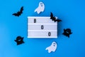 Lightbox with word BOO and halloween party decorations. Bats on dry tree branch with spider net for Halloween on blue