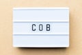 Light box with word COB abbreviation of close of business on wood background