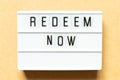 Light box with word redeem now on wood background