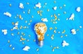 Lightbulb with popcorn kernels on blue Royalty Free Stock Photo