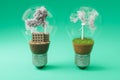 lightbulbs with minature wind turbine and coal-fired power station inside green soil and clouds pollution and smoke renewable