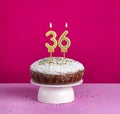 Birthday cake with number 36 candle on pink background