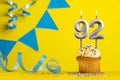 Lighted birthday candle number 92 - Yellow background with blue pennants