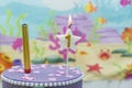 Lighted birthday candle in star shape with blurred background. 1 year anniversary, deep sea theme. Celebration, party and joy