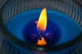 Lighted blue scented candle on a glass container