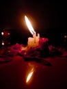 An Lighted candle and red roses on a black background. Candle light concept and weddings Royalty Free Stock Photo