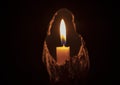 Lighted candle stands in a dark room close-up Royalty Free Stock Photo