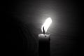 Lighted candle stands in a dark room close-up Royalty Free Stock Photo