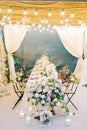 Lighted candles and a huge bouquet of flowers in a vase stand at the festive table on the terrace Royalty Free Stock Photo