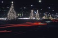 Lighted Christmas trees along roadside and automobile taillights at night, New York