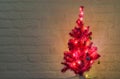 Lighted and decorated christmas tree isolated on a white brick wall background Royalty Free Stock Photo