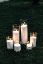 Lighted decorative candles. On the grass are candles burning in glass cylinders