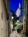 The lighted dome of Sacre Coeur viewed from an alley in nighttime Montmartre, Paris Royalty Free Stock Photo