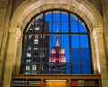 Lighted Empire State Building as viewed through window of New York Public Library Reading Room, on a winter afternoon