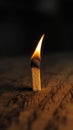 Lighted matchstick rests on a textured brown wooden surface