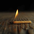Lighted matchstick rests on a textured brown wooden surface Royalty Free Stock Photo
