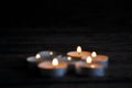 Lighted small candles laid out in a row on a wooden table. Blurriness. Symbol. Still life