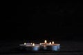 Lighted small candles laid out in a row on a wooden table. Blurriness. Symbol. Still life