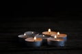 Lighted small candles laid out in a row on a wooden table. Blurriness. Symbol. Still life