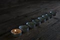 Lighted small candles laid out in a row on a wooden table. Texture. Symbol. Holidays love day
