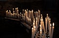 Lighted thin church candles stand in large numbers in a dark room Royalty Free Stock Photo