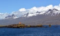 A lighthouse against the background of the Snowy peaks of the basaltic mountains of the eastern fjords in Iceland