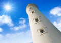 Low angle view of a lighthouse against blue sky with clouds and sun Royalty Free Stock Photo