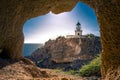 Lighthouse at Akrotiri through a frame of a window of a cave, Santorini.