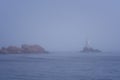 Lighthouse Along Rocky Coastline on Foggy Morning Royalty Free Stock Photo