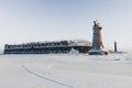 Lighthouse in a calm and desolate winter landscape. A white whitewashed lighthouse over blue sky with clouds