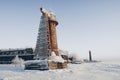 Lighthouse in a calm and desolate winter landscape. A white whitewashed lighthouse over blue sky with clouds