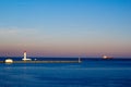 Lighthouse and Cargo ship leaving a harbor in the evening Royalty Free Stock Photo