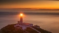 Lighthouse on coastal island with horizon and beautiful sunset Royalty Free Stock Photo