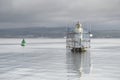 Lighthouse construction tall tower in sea water and bright light under grey sky Royalty Free Stock Photo