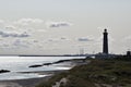 Lighthouse in the distance on one side and the sea and beach on the other side