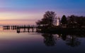 a lighthouse and a dock next to water at sunset or sunrise Royalty Free Stock Photo