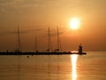 Lighthouse at the end of the pier of stones, sunset over the Adriatic Sea, Croatia, Europe.Orange, calm sea, silhouette, reflectio Royalty Free Stock Photo