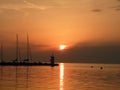 Lighthouse at the end of the pier of stones, sunset over the Adriatic Sea, Croatia, Europe.Orange, calm sea, silhouette, reflectio