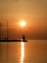 Lighthouse at the end of the pier of stones, sunset over the Adriatic Sea, Croatia, Europe.Orange, calm sea, silhouette, reflect Royalty Free Stock Photo
