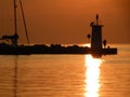 Lighthouse at the end of the pier of stones, sunset over the Adriatic Sea, Croatia, Europe.Orange, calm sea, silhouette, reflectio Royalty Free Stock Photo