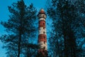 Lighthouse in the forest between the trees. red and white lighthouse Royalty Free Stock Photo