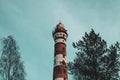 Lighthouse in the forest among the trees. red and white lighthouse Royalty Free Stock Photo
