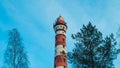 Lighthouse in the forest among the trees. red and white lighthouse Royalty Free Stock Photo
