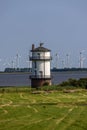 Lighthouse at the grassy shore on the background of wind turbines Royalty Free Stock Photo