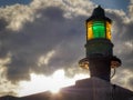 Lighthouse green beacon against cloudy sky