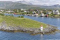 Lighthouse on green cliff and houses on shore, Bronnoysund, Norway