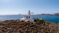 Lighthouse at Kapsali port, Kythera island, Greece. Greek flag waving, rocky hill, sunny day