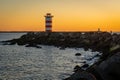 Lighthouse at the north pier Ijmuiden by sunset with a view on south pier in the distance