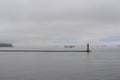 Lighthouse in an ocean bay on a foggy, misty and cloudy grey seascape with horizon at the sea or ocean