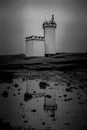 Lighthouse perched on cliff overlooking water and rocks Royalty Free Stock Photo